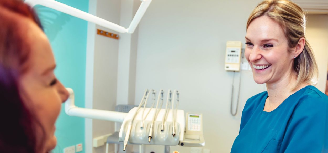 Cosmetic dentist sculpting bonding material on front tooth